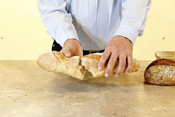 Zwei Hände teilen ein Brot.