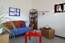 Eine Ecke mit einem Sofa, einem Bücherregal und einem Tisch.